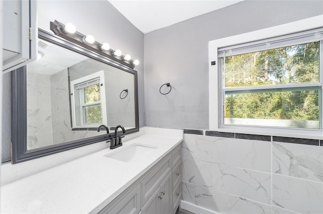 bathroom featuring plenty of natural light, tile walls, and vanity