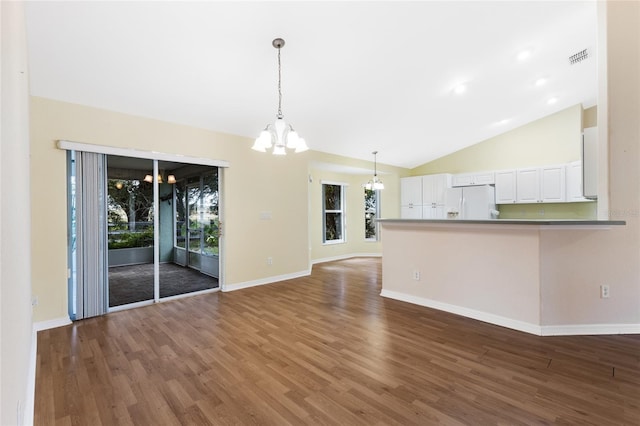 unfurnished living room with dark hardwood / wood-style flooring, lofted ceiling, and a chandelier