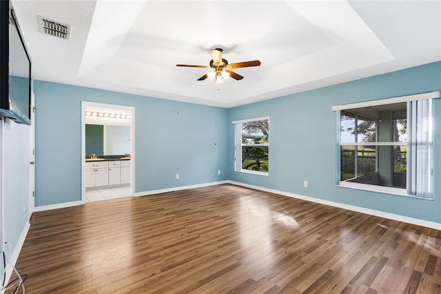 unfurnished bedroom with a raised ceiling, ceiling fan, and wood-type flooring