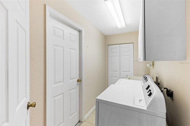 clothes washing area with cabinets, light tile patterned flooring, and washer and dryer