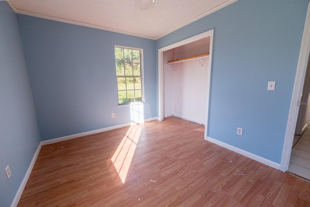 unfurnished bedroom featuring light hardwood / wood-style floors, ornamental molding, a textured ceiling, and a closet