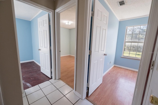 hall featuring crown molding, light hardwood / wood-style floors, and a textured ceiling