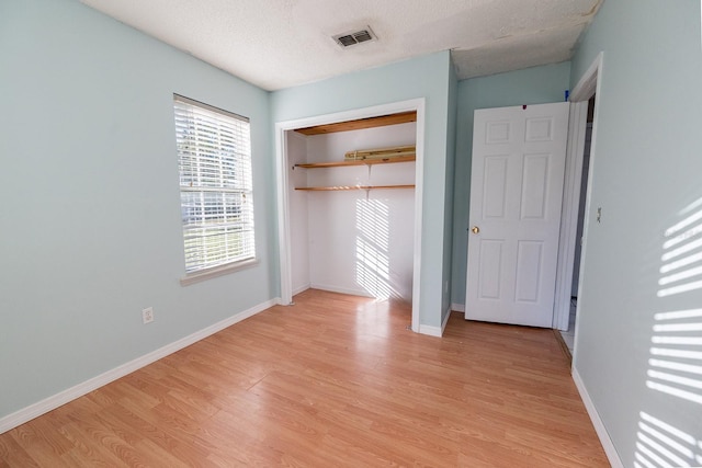 unfurnished bedroom featuring a closet, light hardwood / wood-style flooring, and a textured ceiling