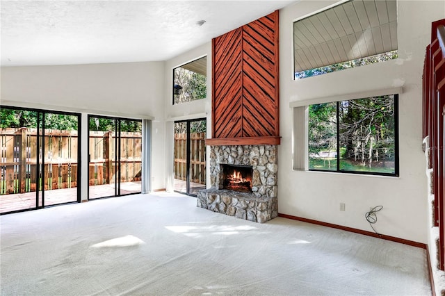 unfurnished living room with carpet flooring, a stone fireplace, a textured ceiling, and high vaulted ceiling