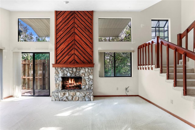 unfurnished living room with carpet, a fireplace, and a high ceiling