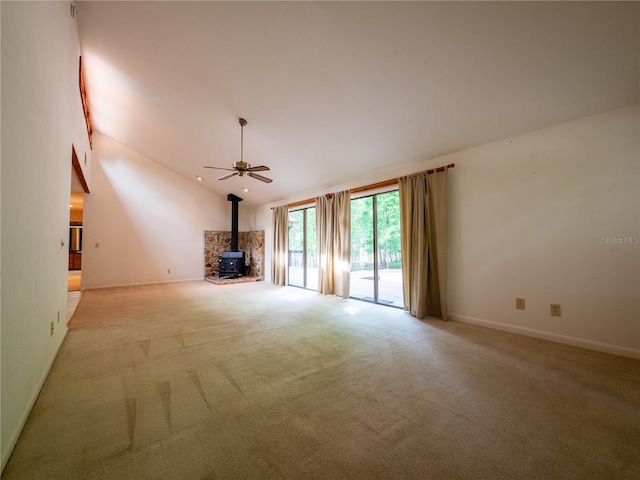 unfurnished living room with light carpet, a wood stove, ceiling fan, and lofted ceiling