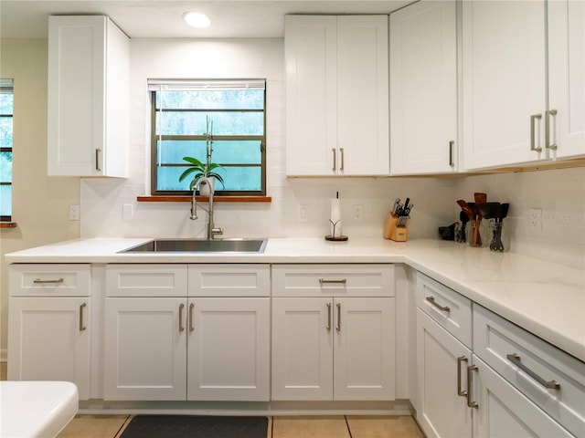 kitchen with tasteful backsplash, sink, white cabinets, and light tile patterned floors