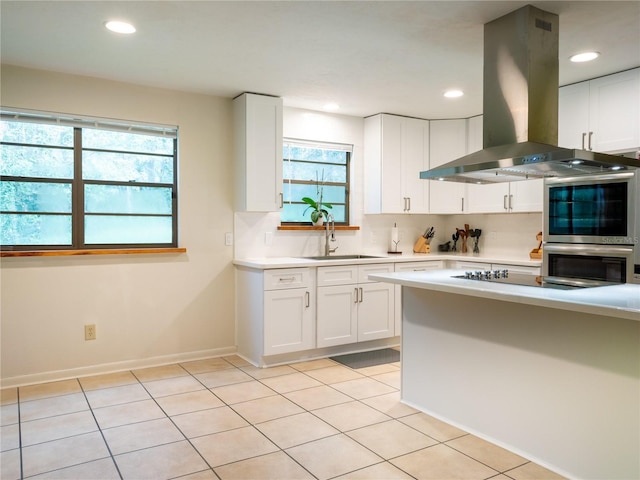 kitchen with island exhaust hood, white cabinets, a wealth of natural light, and sink