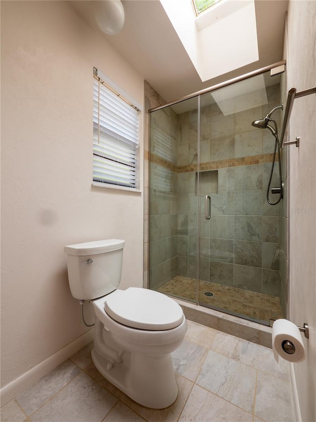 bathroom with a skylight, toilet, and walk in shower