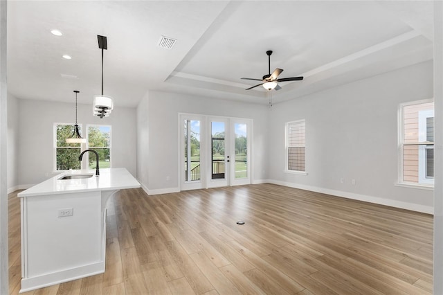 unfurnished living room featuring sink, plenty of natural light, and light hardwood / wood-style flooring