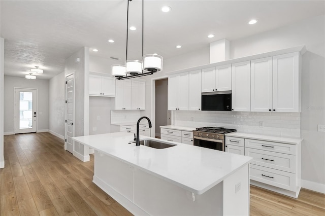 kitchen featuring a center island with sink, sink, light wood-type flooring, and stainless steel appliances