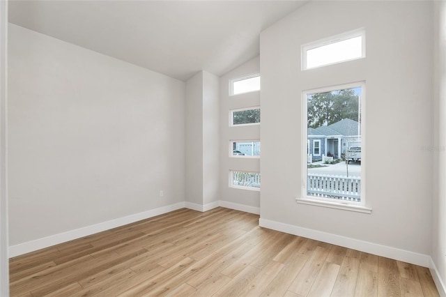 unfurnished room with light wood-type flooring and lofted ceiling