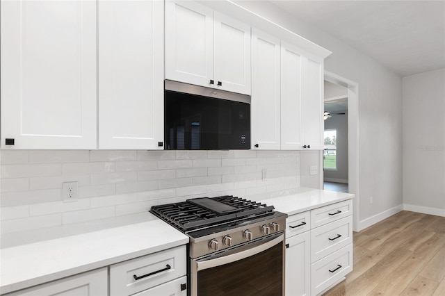 kitchen with backsplash, ceiling fan, appliances with stainless steel finishes, light hardwood / wood-style floors, and white cabinetry