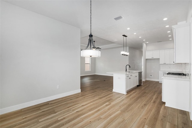 kitchen featuring sink, pendant lighting, light hardwood / wood-style floors, white cabinetry, and an island with sink