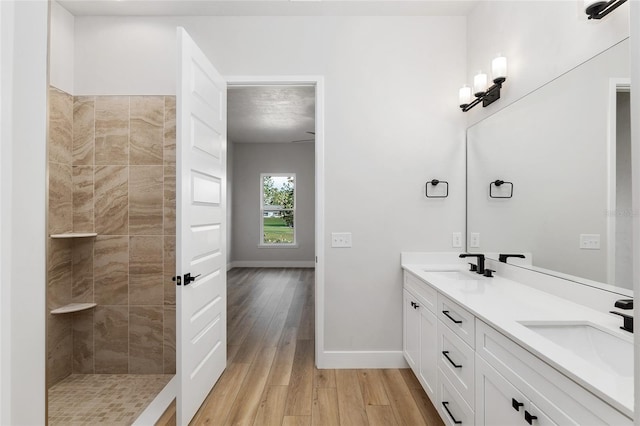 bathroom with a tile shower, vanity, and hardwood / wood-style flooring