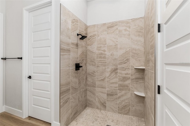 bathroom with wood-type flooring and tiled shower