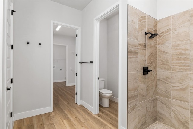 bathroom featuring toilet, wood-type flooring, and tiled shower