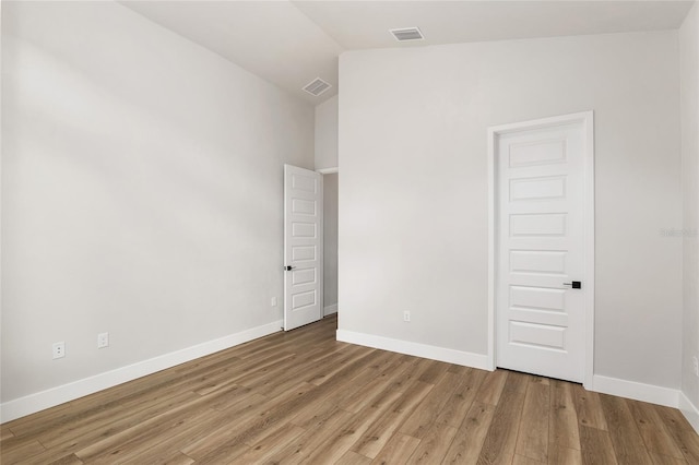 empty room with light hardwood / wood-style flooring and lofted ceiling