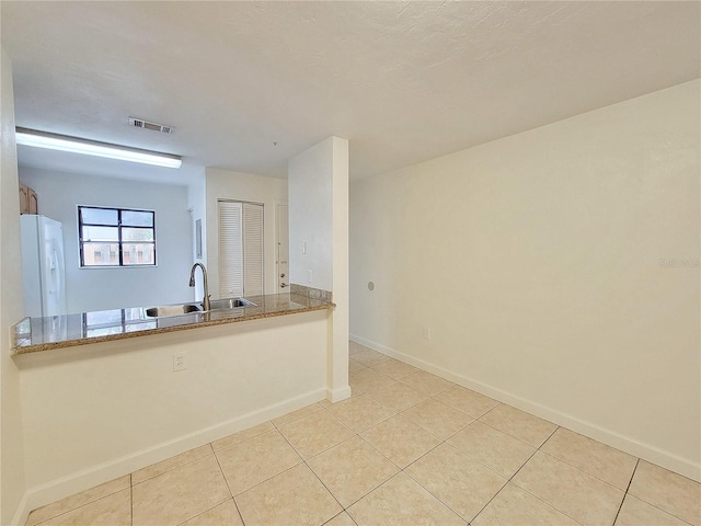 kitchen featuring light tile patterned floors, white fridge with ice dispenser, and sink