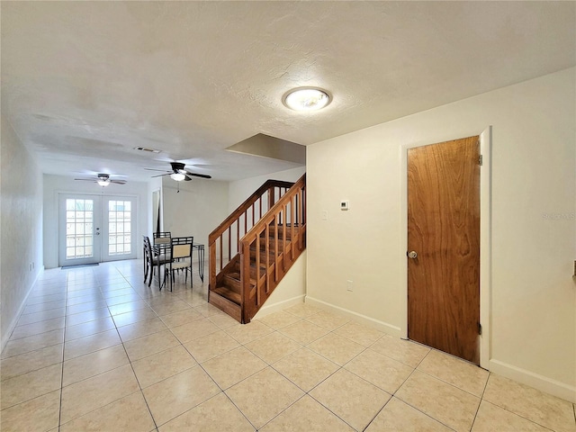 interior space featuring tile patterned flooring, french doors, a textured ceiling, and ceiling fan