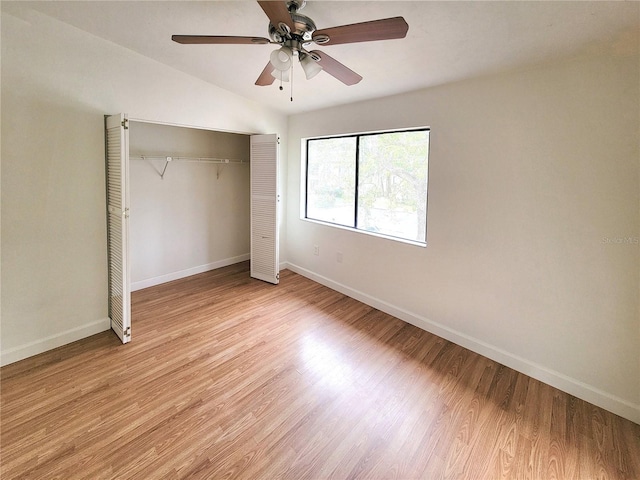 unfurnished bedroom with vaulted ceiling, a closet, light hardwood / wood-style flooring, and ceiling fan