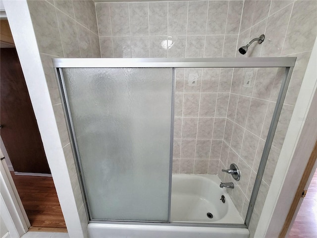 bathroom with hardwood / wood-style flooring and combined bath / shower with glass door