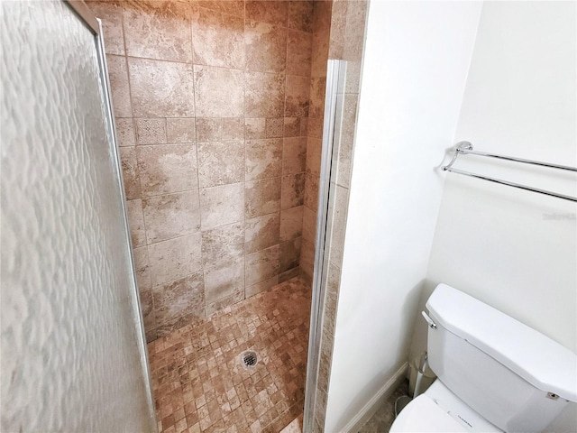 bathroom with a tile shower and toilet