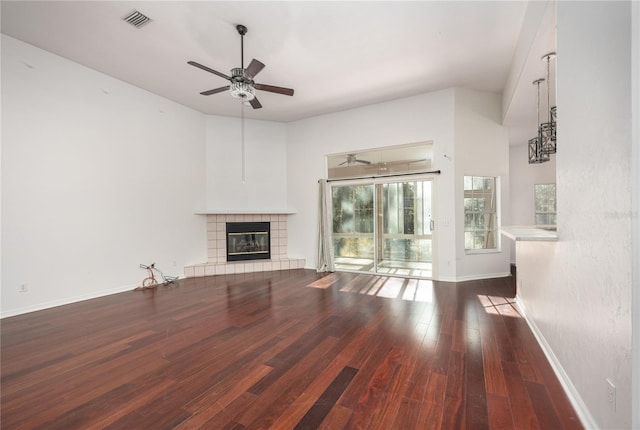 unfurnished living room with a tile fireplace, dark hardwood / wood-style flooring, and ceiling fan