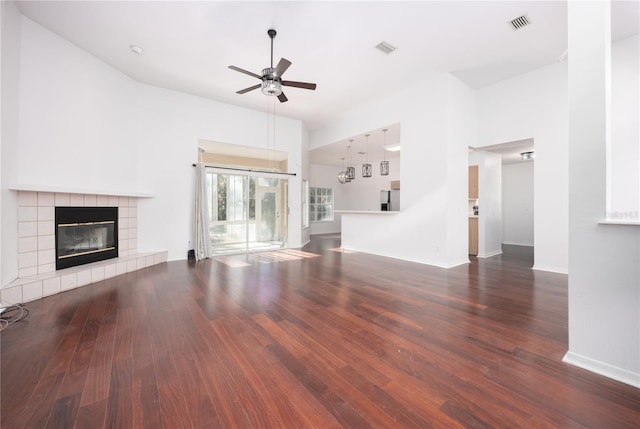 unfurnished living room with a tile fireplace, ceiling fan, and dark hardwood / wood-style floors