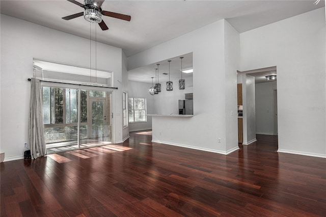 unfurnished living room with ceiling fan, dark hardwood / wood-style flooring, and a towering ceiling