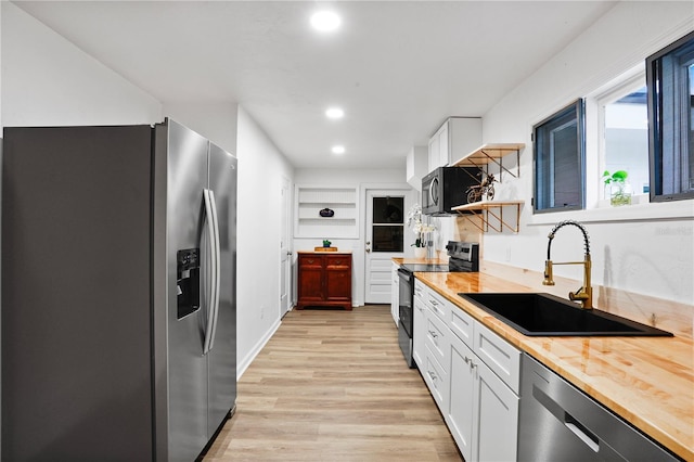 kitchen featuring white cabinetry, sink, wood counters, light hardwood / wood-style flooring, and appliances with stainless steel finishes