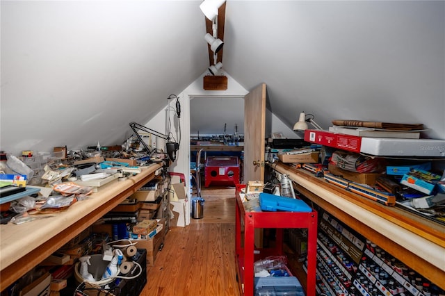 interior space with a workshop area, vaulted ceiling, and hardwood / wood-style flooring