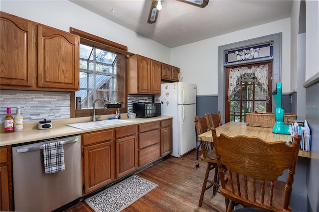 kitchen with sink, dark wood-type flooring, stainless steel dishwasher, white fridge, and decorative backsplash