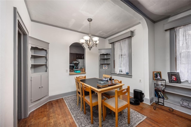 dining space featuring a notable chandelier, dark hardwood / wood-style flooring, and ornamental molding