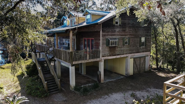 rear view of house with stairway, driveway, and metal roof