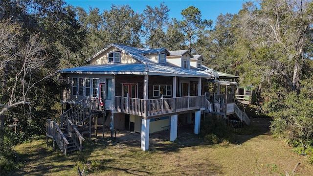 back of property with metal roof, a lawn, a wooden deck, and stairs