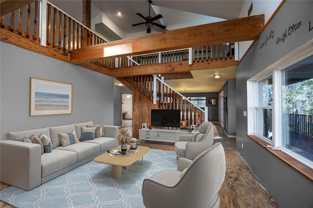 living room with ceiling fan, a towering ceiling, and stairs