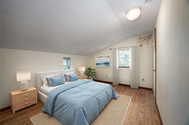 bedroom with lofted ceiling, wood finished floors, and baseboards