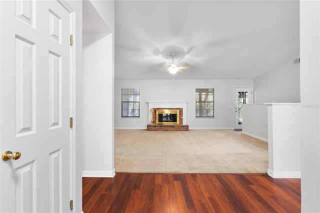 unfurnished living room featuring ceiling fan, dark wood-type flooring, and a brick fireplace