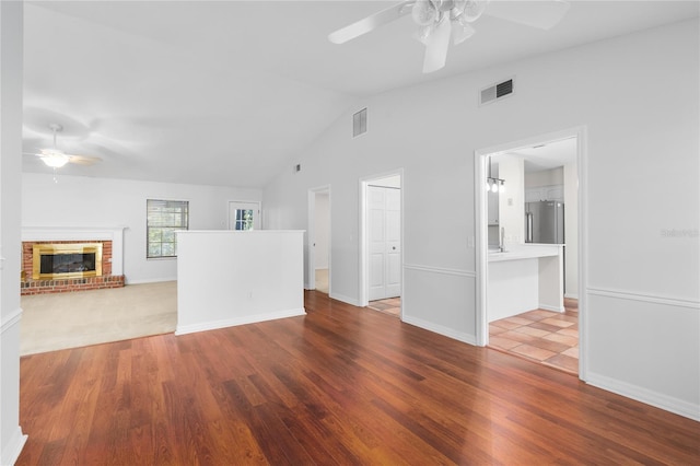 unfurnished living room featuring ceiling fan, a fireplace, light hardwood / wood-style floors, and vaulted ceiling