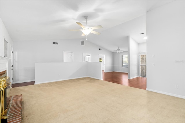 unfurnished living room featuring carpet flooring, ceiling fan, vaulted ceiling, and a brick fireplace