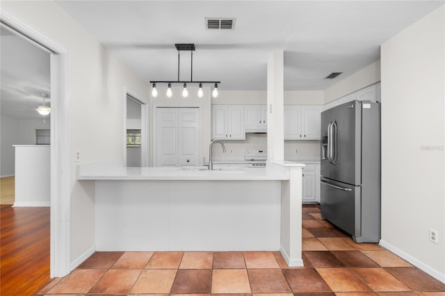 kitchen with white cabinets, stainless steel fridge, kitchen peninsula, and hanging light fixtures