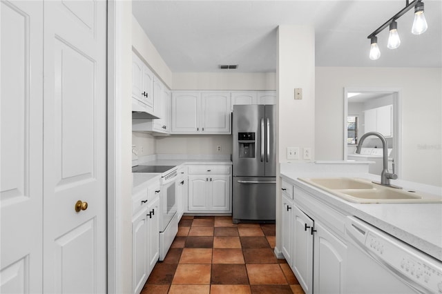 kitchen with sink, white cabinets, dark tile patterned flooring, and white appliances