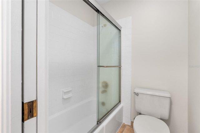 bathroom featuring combined bath / shower with glass door and toilet