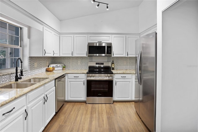 kitchen with white cabinets, appliances with stainless steel finishes, vaulted ceiling, and sink