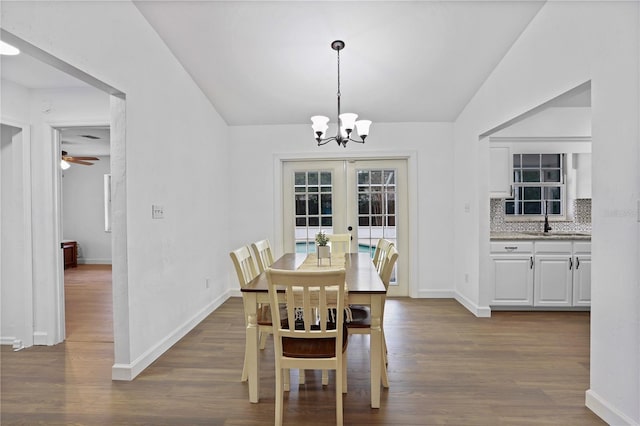 dining area featuring dark wood-type flooring, french doors, ceiling fan with notable chandelier, sink, and vaulted ceiling