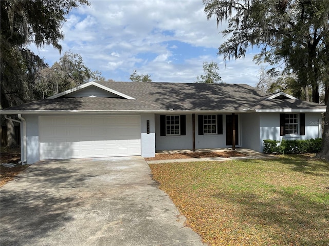 ranch-style house with roof with shingles, stucco siding, a front yard, a garage, and driveway