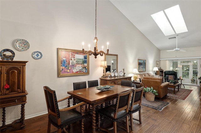 dining room featuring ceiling fan with notable chandelier, a skylight, high vaulted ceiling, and dark wood-type flooring