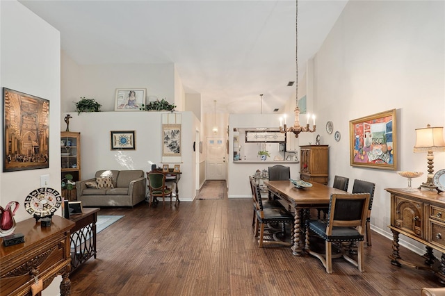 dining room with dark hardwood / wood-style floors, a high ceiling, and an inviting chandelier