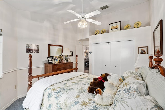 carpeted bedroom featuring ceiling fan, a closet, and a towering ceiling